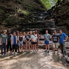 A group of students pose for a photo with Chestnut Ridge Park's eternal flame. 