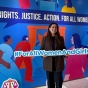 Senay Imre stands in front of a colorful display for the United Nations Commission on the Status of Women. She holds a sign that reads &ldquo;#ForAllWomenAndGirls.&rdquo; Behind her, large text reads &ldquo;RIGHTS. JUSTICE. ACTION. FOR ALL WOMEN AND GIRLS,&rdquo; along with &ldquo;CSW70 Commission on the Status of Women 9&ndash;19 March 2026.&rdquo;. 
