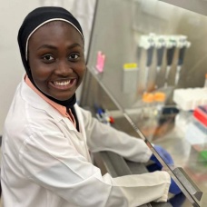 Aisaha Makama smiling in a research lab. 