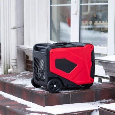 A portable generator sits on steps outside a home in the winter. 