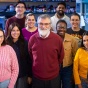 A group portrait taken inside a chemistry laboratory shows nine people standing close together and smiling at the camera. 