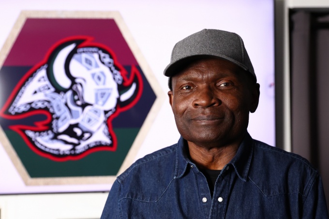 George Afedzi Hughes stands in front of his redesigned Buffalo Sabres &ldquo;goathead&rdquo; logo featuring Pan-African colors and African symbols for Black History Month. 
