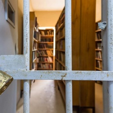 A prison libray behind a barred and locked door. 