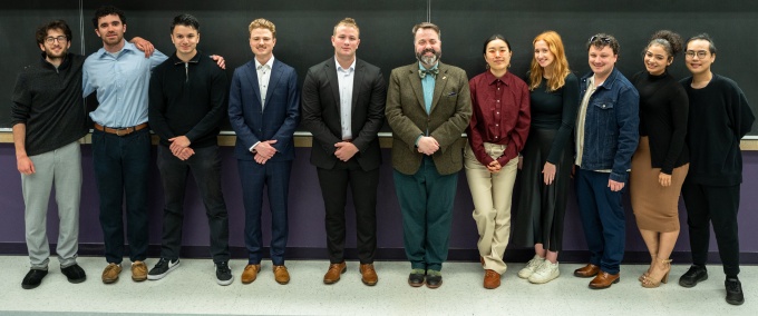 The students from Integrating PPE (PHI 485), spring 2024, stand together in a classroom with their professor.