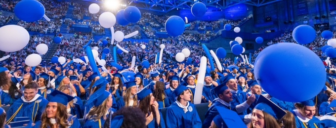 Graduates at commencement with balloons. 