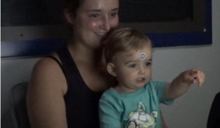 An infant sitting on his mother's lap during a study. 