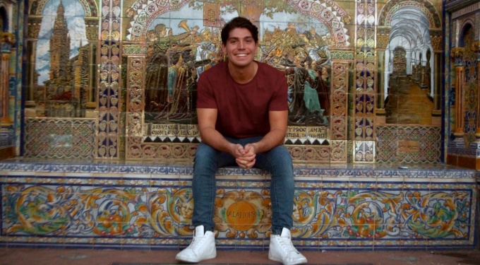 Student sitting in front of Spanish mosaic.