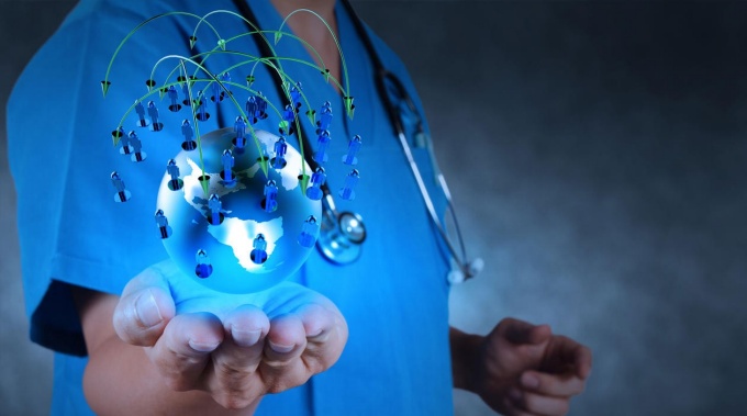 Person in scrubs with a stethoscope holding a digital globe. 