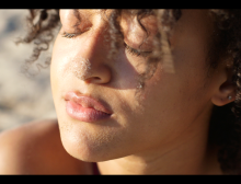 Close photograph of student dancer Nina Tucker, a young black woman, with her eyes closed in the sun. 