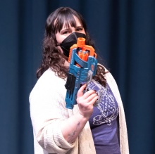 Danielle Rosvally on set holding a toy gun. 