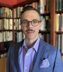 Professor Hoxworth standing in front of a bookcase. 
