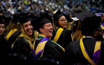 Graduate Students in graduate apparel laughing during their ceremony. 