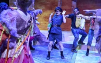 three dancers in blue dresses with fedoras. 