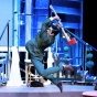 Male performer on stage, comedically swinging an axe. 