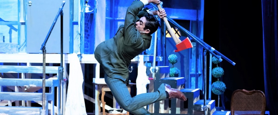 Male performer on stage, comedically swinging an axe. 