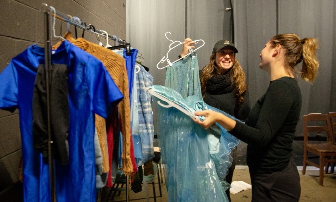 Students backstage with costume rack. 