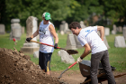 Mary Odrzywolski (left, green hat) director of the Office of Study Abroad Programs, helps move some topsoil at Concordia Cemetery.