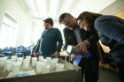 Contest founder and chemistry faculty member Jason Benedict (center) shines a light on a crystal submitted for the contest's "coolest crystal" category. Andrea Markelz, professor of physics and a judge, looks on. Photo: Douglas Levere