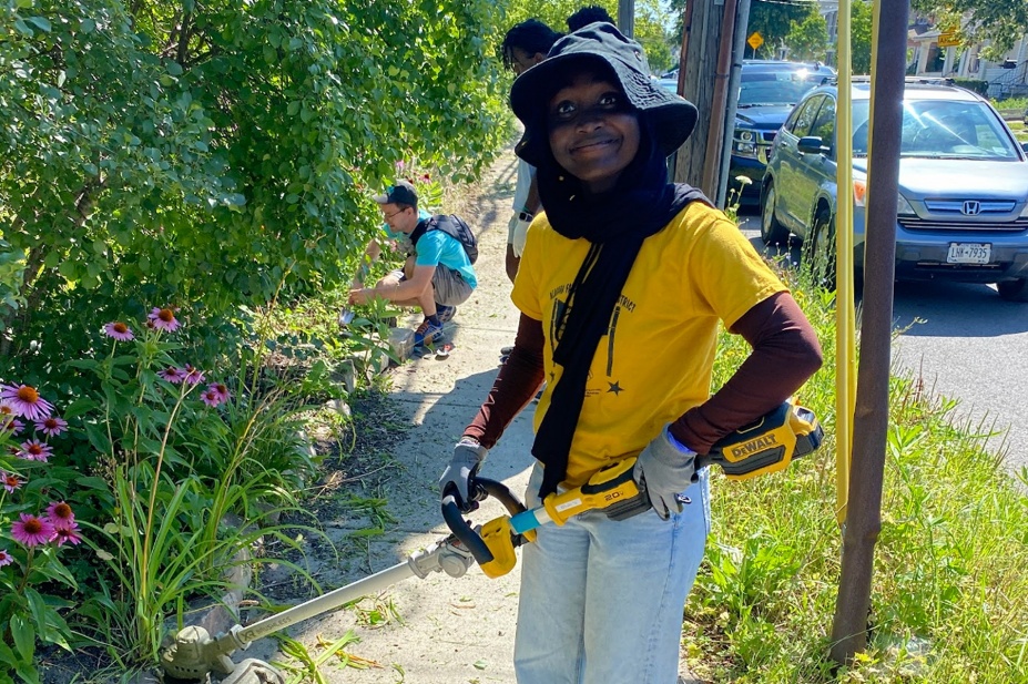 Aisha Makama uses a weed whacker during a community service project.
